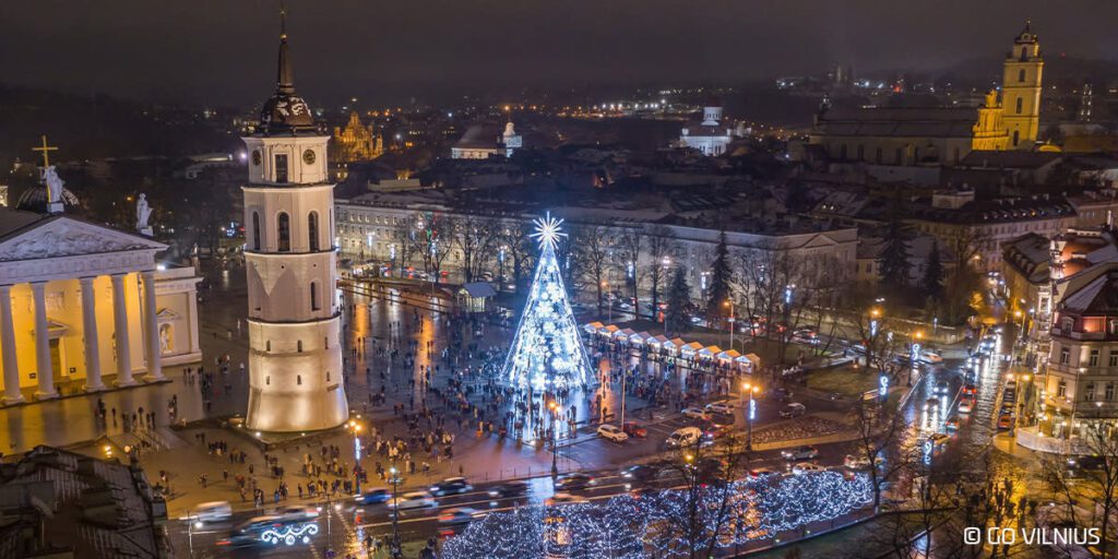 A Large White Tower With A Christmas Tree In The Middle Of A City