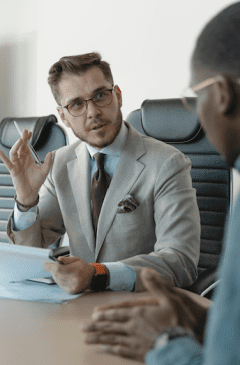 a man in a suit and tie sitting at a table with a pen in his hand