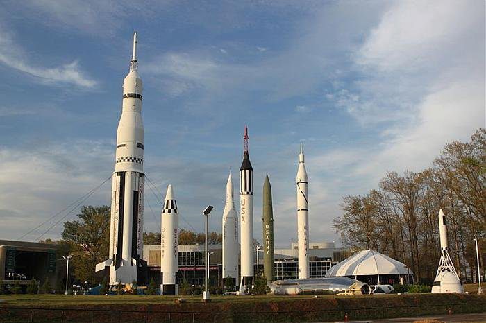 a large white rocket model with Kennedy Space Center in the background