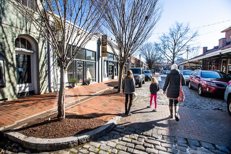 A Group Of People Walking On A Brick Street